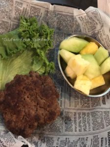 A picture of a naked burger & a bowl of fruit.