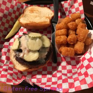 A cheeseburger with bacon and pickles and a side order of tater tots.