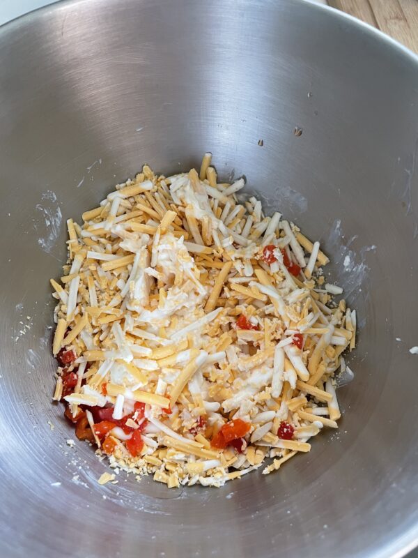 Shredded dairy-free cheese, pimentos, and dairy-free cream cheese in mixing bowl